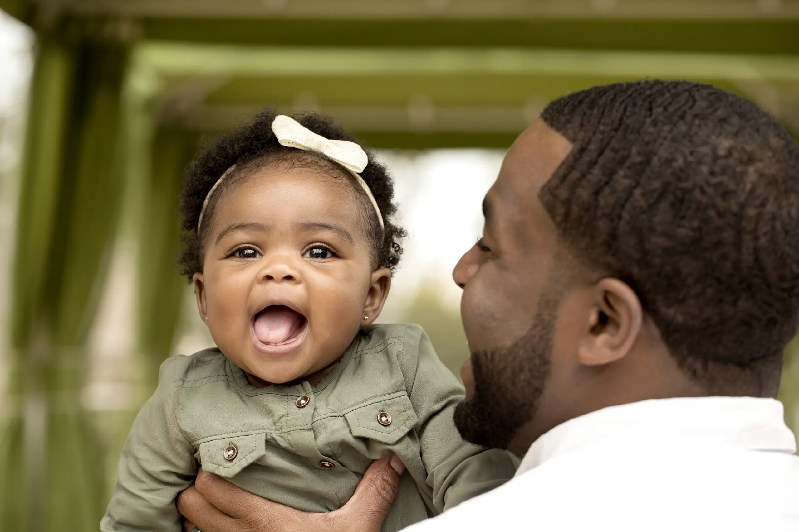 Father holding his smiling baby daughter into the camera